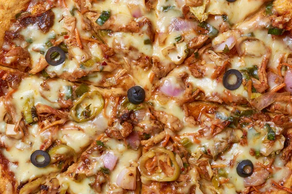 close-up of spicy devilled chicken pizza, freshly made pizza mixed with grilled vegetables, olives and double layers of mozzarella cheese, taken straight from above in full frame, food background