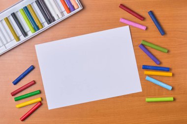 Pastel boya kalemleri ve boş ya da boş beyaz bir kağıt, arka planda boya kalemleri ve kutular, yukarıdan kopyalanmış boşluk ile alındı.