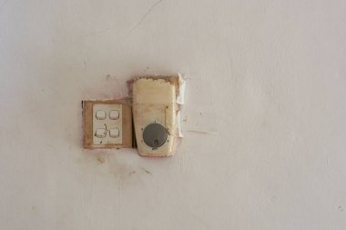 Hasarlı ve onarılmış ışık ve tavan vantilatörü kirli beyaz bir duvarda düğmeler, fotokopi alanı ile profesyonel olmayan elektrikçi kavramı
