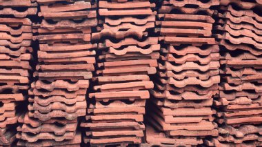 Yığılmış eski çatı kiremitlerinin kenar görüntüsü, ıskartaya çıkarılmış kırmızı toprak çatı kiremitlerinin soyut arka planı, doğal kil ve dayanıklılıktan yapılmış, tam çerçeve içinde alınmış.