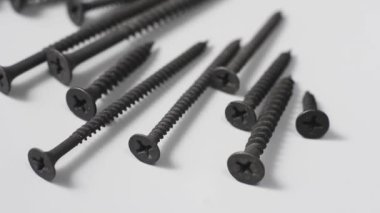 Nötr gri arka plana saçılmış metal vidalar, siyah alçıpan fosfat kaplı bina pasından korunmak için, endüstriyel konsept