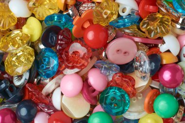 Çeşitli renk ve tasarım düğmeleri, parlak ve canlı renkli plastik dikiş aksesuarları giysi ve el işi projeleri için yukarıdan tam kare çekilmiş.