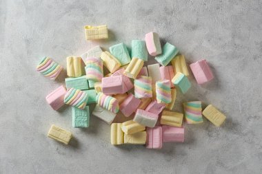 Beyaz desenli yüzeyde marşmelovlar, renkli yumuşak şeker şekerlemeleri farklı şekil ve boyutlarda, şekerleme parçacıkları üst görünümde kopya alanı