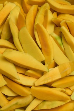 Çeşitli mutfak kullanımları için dilimlenmiş olgun mango parçaları, kesilmiş deri yığını tatlılar için tropik meyveler salatalar, baharatlar, içecekler, yukarıdan gelen yiyecek arka planı.