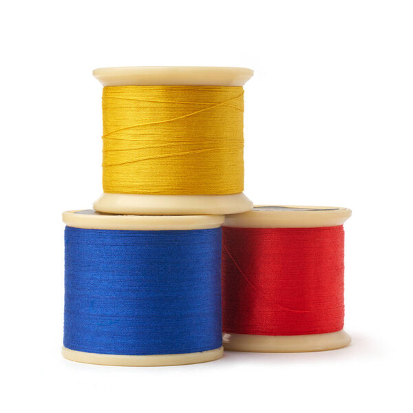 первичные цвета катушки хлопчатобумажной вышивки нитки изолированные белый фон, синий, желтый и красный, используемые в деталях сшивания или декоративной ткани и текстильной промышленности в различных цветах