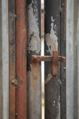 Metal kapının eski paslı mandal kilidine yakın çekim, paslanmış kilit donanımı yumuşak odak noktasında ve boşluğu kopyala