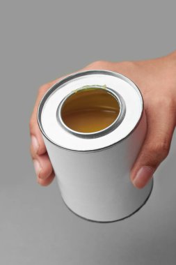 hand holding yellow adhesive in silver tin can isolated gray background, mock-up template of synthetic glue metal container with blank label clipart