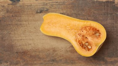 Tereyağlı kabak ikiye bölünmüş canlı portakal eti ve tohumlar kesim tahtası arka planında, yukarıdan kopyalanmış