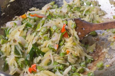 Yakın planda sebze kızartması, doğranmış lahana, yeşil fasulye, soğan ve biber, yumuşak odaklı ahşap spatula ile canlı ve besleyici yemek pişirme