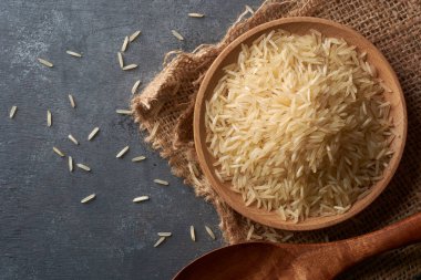 Yakın plan ham basmati pirinç tanecikleri siyah desenli masa üstü yüzeyi üzerinde, kremsi beyaz renkli kumlu yiyecekler doğrudan yukarıdan kopyalanmış boşluk ile alınmış.