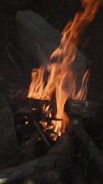 Açık hava kamp ateşine yakın çekim, yemek pişirmek için kullanılan, çay için kaynar su, sıcak ve genel aktiviteler, kamp için yanan odun.