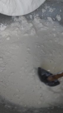 Pürüzsüz pirinç unu karışımı geleneksel tatlı için temel görevi gören yumuşak hamur hamuru yapmak için bir tencerede suyla karıştırılıyor.