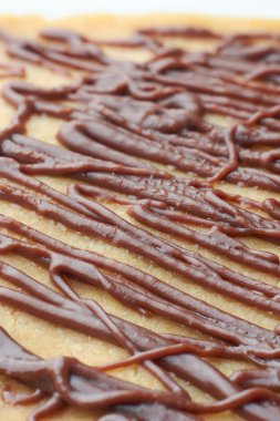 Koyu kahverengi çikolata kaplama pasta yüzeyine yakın plan, çapraz yoğun düzensiz dalgalı desen çizgileri, bulanık arkaplan ile yumuşak odak