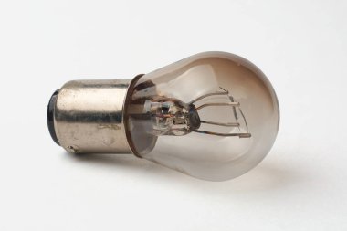 Eski akkor çift lifli ampulün yakın çekim makro görüntüsü, gümüş metal tabanlı izole edilmiş beyaz zemin, içinde iki iplik var.