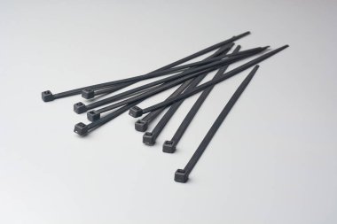 Siyah plastik kablo ya da kablo bağları gri arkaplana saçılmış, bağlayıcılar kabloları ya da kabloları bir araya getirmek için kullanılıyor, kopyalama alanı ile yumuşak odak, kablo yönetimi kavramı