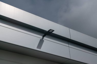 Düz çatılı ve metal ön cepheli modern sokak lambası, galvanizli çelik çatılı ve kornikal önlü bir bina. çatı yanıp sönüyor