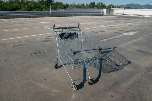 stock image The shopping cart in empty parking lot. shopping cart wanted, ready for shopping or synonymous with trade crisis, inflationary economy, news of the crisis of consumption. hypermarket closed for the holidays. shopping mall news