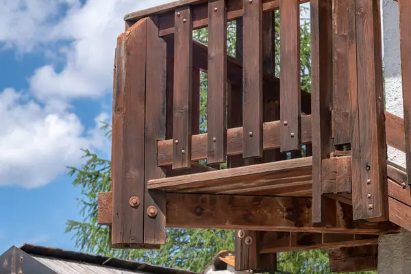 Karakteristik bir dağ evinin ön cephesi boyunca sert ahşap kirişler ve korkuluklarla kaplı dış ahşap merdiven rüzgarları, kırsal Alp binasının güzelliğini artırıyor..