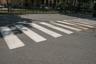 Beyaz zebra geçişleri asfalt üzerinde duruyor, yayalar için bir güvenlik ve ulaşılabilirlik sembolü. Şehir trafiğinde yaya geçidi, trafik işaretleri kazaları sınırlamak için kullanışlı. Web haber olayları