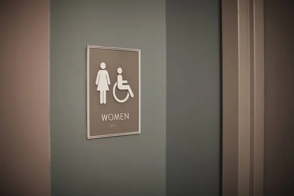 壁の背景に女性とトイレの看板 — ストック写真
