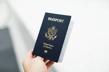 hand holding a passport with a flag of the united states of america