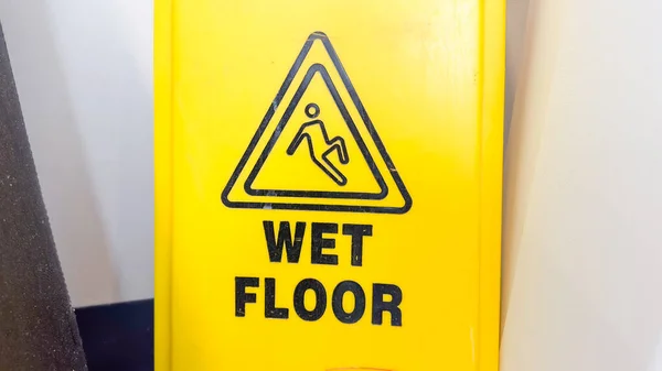 黄色のぬれた床の徴候は 滑りやすく 潜在的に危険な領域を示す 注意と警告の象徴です それは安全性 公衆の注意と警戒の必要性を表しています — ストック写真