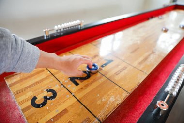 Shuffleboard, oyuncuların sayı bölgelerine ulaşmak için diskleri dar bir sahada kaydırdıkları bir hassasiyet ve strateji oyunudur. Spor doğruluk ve sabır arayışını temsil eder.