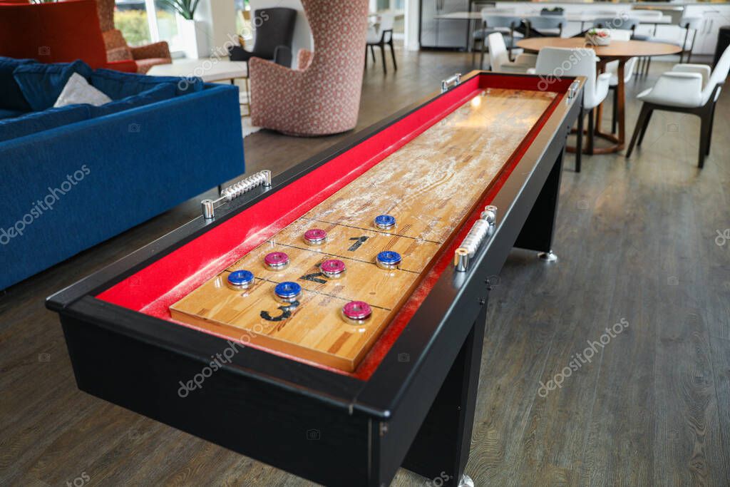 Shuffleboard es un juego de precisión y estrategia, donde los jugadores deslizan discos pesados