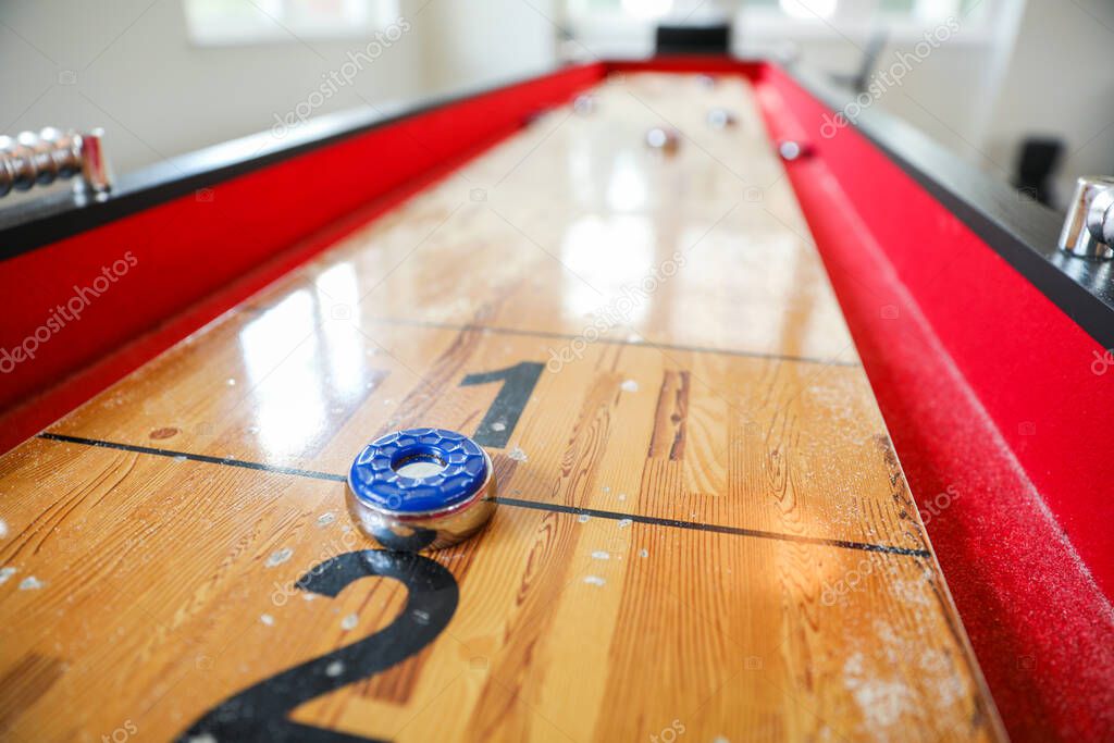 Shuffleboard es un juego de precisión y estrategia, donde los jugadores deslizan discos pesados