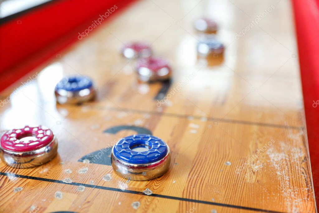 Shuffleboard es un juego de precisión y estrategia, donde los jugadores deslizan discos pesados
