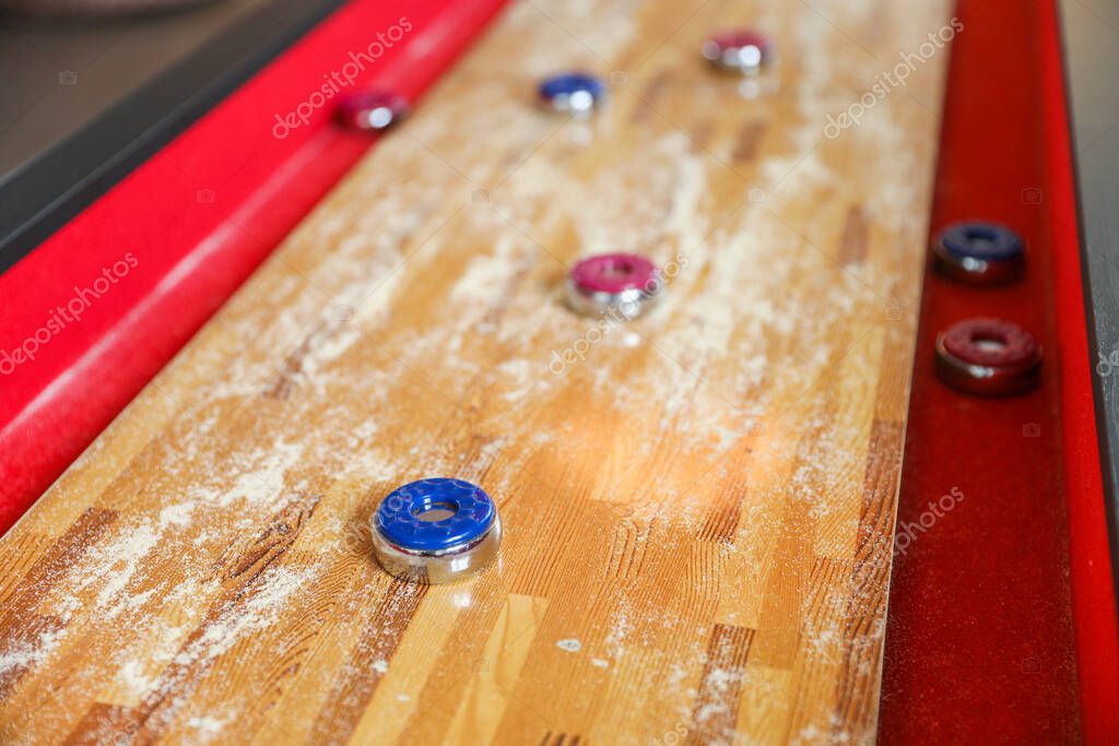 Shuffleboard es un juego de precisión y estrategia, donde los jugadores deslizan discos pesados