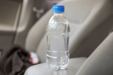 Güzel havalarda etiketlenmemiş plastik su şişesi kolaylığı, susuzluğu ve çevresel endişeleri simgeler. Sorumlu tüketim ve farkındalık ihtiyacını temsil eder.