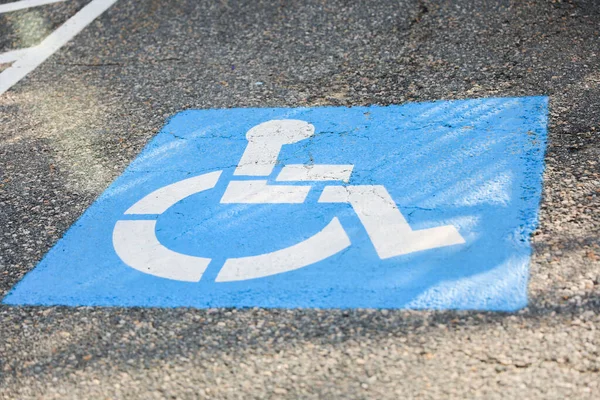 A blue and white wheelchair symbol on a signpost, representing accessibility and inclusivity for individuals with disabilities on the streets