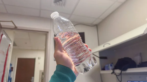 紧紧抓住一个塑料水瓶 象征着环境影响和减少一次性塑料废物的迫切性 — 图库照片