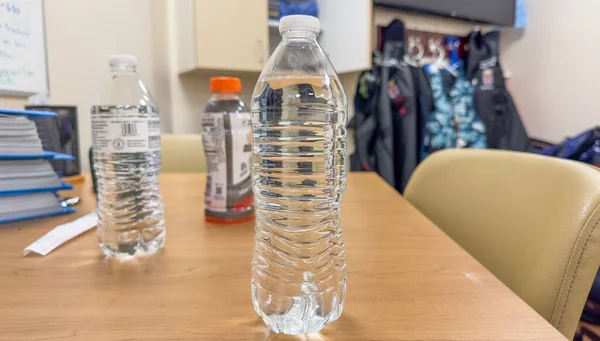プラスチック製の水ボトルを手でしっかり握って環境への影響と緊急性を象徴し使い捨てプラスチックごみを減らす — ストック写真