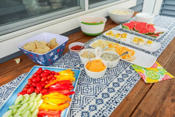 potluck spread of fresh veggies, fruits, and dips, complemented by crunchy chips, popcorn, and eggs, symbolizing diversity, nourishment, and shared experiences