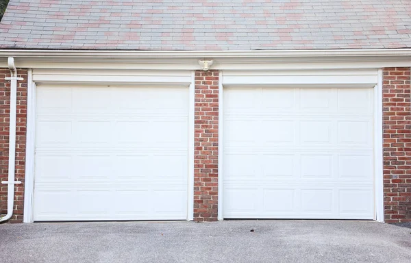 Beyaz metal kapıları olan iki beyaz garaj kapısı.