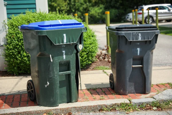 two black and white bins for garbage in a row.