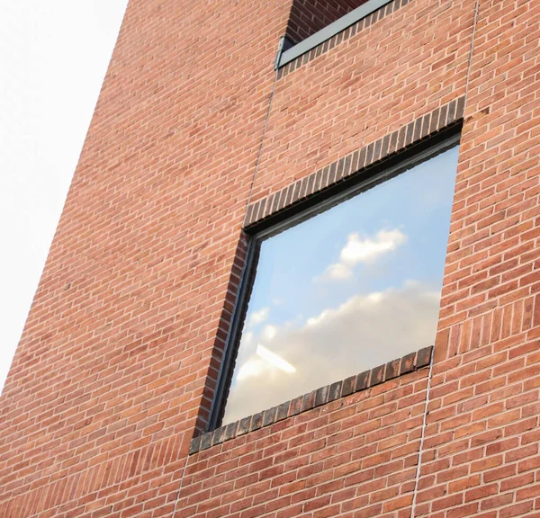 modern brick wall and window with a red roof.