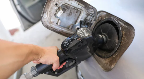 close up of woman hands holding fuel nozzle in gas station