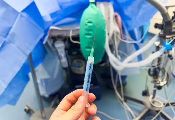 close up of a medical equipment with a needle for surgery in the background. the doctor is holding a medical needle with a syringe for