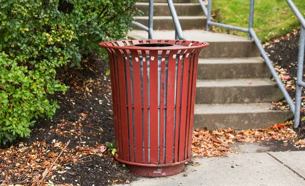 red plastic trash can at a public park