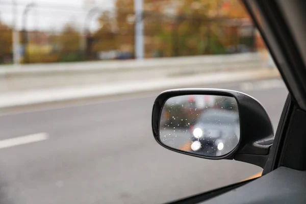 view of car mirror on street with blurred car