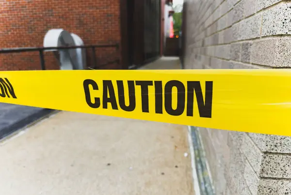 yellow tape with black warning sign on the background of the building.