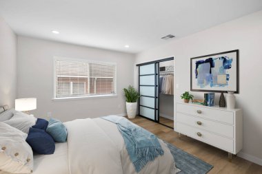 Mobilyaları ve beyaz duvarları olan modern bir yatak odası.