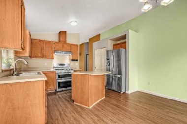 Ahşap dolapları ve yeşil duvarları olan modern mutfak..