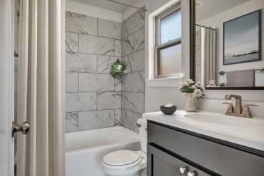 Gri duvarları ve aynası olan modern bir banyo.