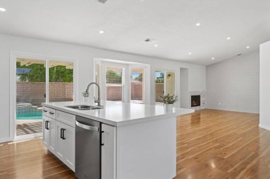 Ahşap zemini ve beyaz duvarları olan modern mutfağın içi..