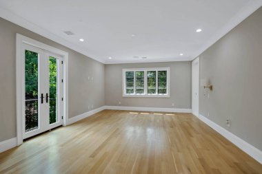 Gri duvarları ve ahşap zemini olan boş bir oda.