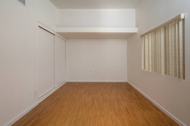 Beyaz duvarları ve tahta zemini olan boş bir oda..